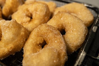 Altın çörekler, tel askıya serpilmiş şeker serpiştirilmiş. Bu taze kızarmış çöreklerin içi yumuşak, dışı kıtır kıtır, bayram için mükemmel..