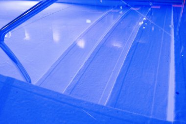 Mor ışıklarla aydınlatılmış modern bir yüzme havuzu, huzurlu bir gece ortamı sunuyor..