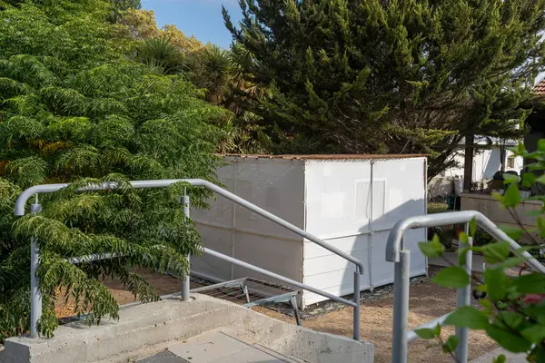 İnsanlar Sukkot şenliklerine hazırlanırken, geleneksel suka yeşil alanlarla çevrili bir bahçede duruyor. Yapısı, basit ama davetkar, mevsimsel atmosfere ekleniyor.