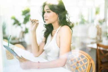 Güzel Asyalı serbest meslek sahibi insanlar yazın beyaz kolsuz elbise giyen iş kadını mankenler internet gezmek, sohbet etmek ve kafede blog yazmak için günlük işler yapıyorlar..