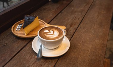 Sütlü sütlü sütlü sütlü sütlü sıcak kahve ve ahşap masanın üstünde ev yapımı çikolatalı kek ahşap masa. İş konsepti sırasında bir kafede kahvaltı olarak.