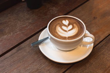 Sütlü sütlü sütlü sütlü sıcak kahve fincanı ahşap masanın üstünde. İş konsepti sırasında bir kafede kahvaltı olarak.