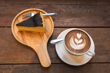 Sütlü sütlü sütlü sütlü sütlü sıcak kahve ve ahşap masanın üstünde ev yapımı çikolatalı kek ahşap masa. İş konsepti sırasında bir kafede kahvaltı olarak.