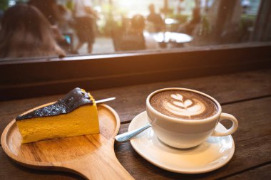 Sütlü sütlü sütlü sütlü sütlü sıcak kahve ve ahşap masanın üstünde ev yapımı çikolatalı kek ahşap masa. İş konsepti sırasında bir kafede kahvaltı olarak.
