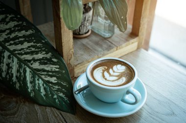 Sütlü sütlü sütlü sütlü sıcak kahve fincanı ahşap masanın üstünde. İş konsepti sırasında bir kafede kahvaltı olarak.