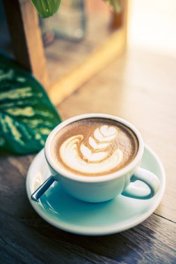 Sütlü sütlü sütlü sütlü sıcak kahve fincanı ahşap masanın üstünde. İş konsepti sırasında bir kafede kahvaltı olarak.