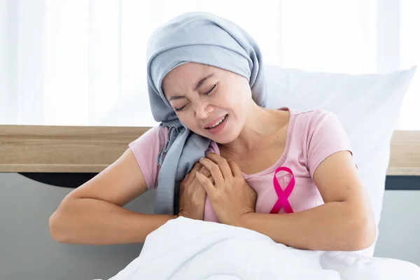 a asian women disease mammary cancer patient acute Heart attack symptom stick pink ribbon wearing headscarf After treatment to chemotherapy sit on bed In the bedroom at the house
