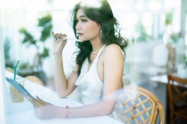 Güzel Asyalı serbest meslek sahibi insanlar yazın beyaz kolsuz elbise giyen iş kadını mankenler internet gezmek, sohbet etmek ve kafede blog yazmak için günlük işler yapıyorlar..