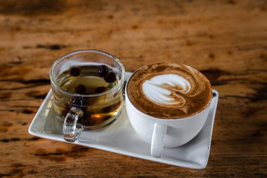 Sütlü sütlü sütlü sütlü sütlü sıcak kahve fincanı, ahşap masanın üstünde sıcak çay. Kahve dükkanında, iş konsepti sırasında, kahvaltı olarak.