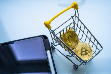 Altın bitcoin ya da kripto para ya da alışveriş arabasındaki semboller ve beyaz masadaki tablet yakın plan. Gelecek para birimi kavramı.