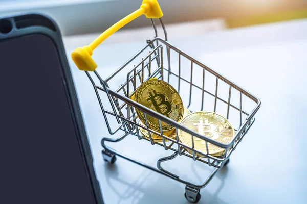 stock image Close-up of Golden bitcoins or cryptocurrency coin or symbols in shopping cart and tablet in white table. Future currency concept.