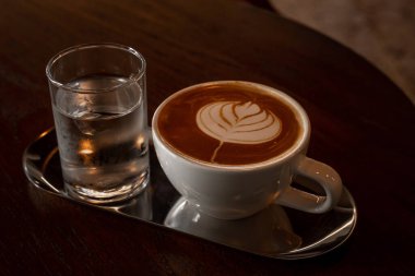 Sütlü sütlü sütlü sütlü sıcak kahve fincanı ahşap masanın üstünde. İş konsepti sırasında bir kafede kahvaltı olarak.