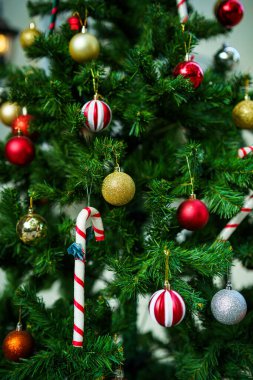 Mutlu Noel 'ler, renkli baloları, hediye kutusunu ve Noel kutlaması paketini kapatın, Noel ve Yeni Yıl boyunca Yeşil Noel ağacı arka planında çan süslemesi.