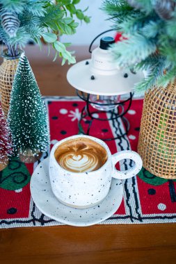 Sıcak kahveli latte ile sütlü sütlü sütlü bardakta Xmas dekorları ve ahşap masa üzerindeki Xmas ağacı süslemeleri Mutlu Noeller ve yeni yılı kutluyoruz..