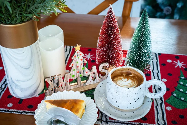 Sütlü sütlü sütlü sütlü sütlü sıcak kahve ve Noel süslü ev yapımı cheesecake ve Noel 'i ve yılbaşını kutlamak için ahşap masanın üzerinde Xmas ağacı süslemeleri..