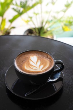 Sütlü sütlü sütlü sütlü sıcak kahve fincanı siyah tahta masanın üstünde. İş konsepti sırasında bir kafede kahvaltı olarak.