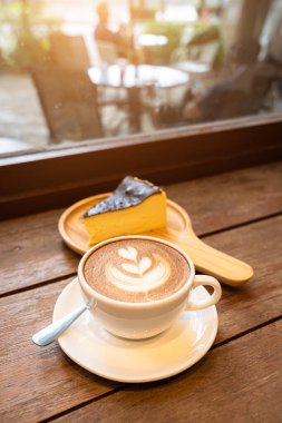 Sütlü sütlü sütlü sütlü sütlü sıcak kahve ve ahşap masanın üstünde ev yapımı çikolatalı kek ahşap masa. İş konsepti sırasında bir kafede kahvaltı olarak.