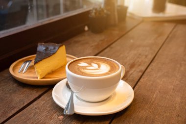 Sütlü sütlü sütlü sütlü sütlü sıcak kahve ve ahşap masanın üstünde ev yapımı çikolatalı kek ahşap masa. İş konsepti sırasında bir kafede kahvaltı olarak.