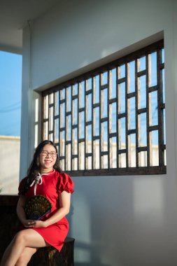 Güzel bir portre gülümsüyor Asyalı genç bir kadın geleneksel Çin nişanı takıyor ve Çin Yeni Yıl Festivali için Çin lokantasında bir Fanning tutuyor..