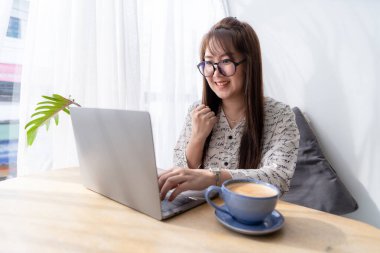 Asyalı serbest iş adamlarının mutlu başarılı işleri iş kadınları kahve fincanı ve akıllı telefonla dizüstü bilgisayarla çalışma cesaretini dile getirdi.