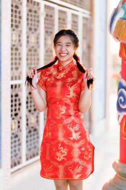 Portre güzel sevimli gülümseme kırmızı keongsam elbise giyen Asyalı genç kadın Çin Yeni Yıl Festivali için geleneksel dekorasyon Çin kültürünü Tayland 'daki Çin tapınağında kutluyor.