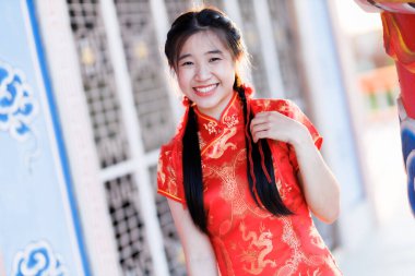 Portre güzel sevimli gülümseme kırmızı keongsam elbise giyen Asyalı genç kadın Çin Yeni Yıl Festivali için geleneksel dekorasyon Çin kültürünü Tayland 'daki Çin tapınağında kutluyor.