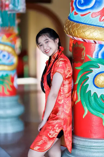 Güzel, şirin bir portre gülümseyen Asyalı genç bir kadın geleneksel Çin cheongsam süslemesi takıyor ve Tayland 'da Çin Yeni Yıl Festivali için Çin Fanning' i düzenliyor.