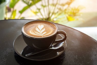 Sütlü sütlü sütlü sütlü sıcak kahve fincanı siyah tahta masanın üstünde. İş konsepti sırasında bir kafede kahvaltı olarak.