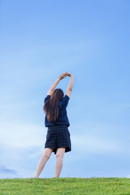 Mutlu Esneme Rahatlığı Asyalı Kadın Dinlenme Portresi Açık hava parkında açık mavi gökyüzü arka planında koyu mavi elbise giyer.