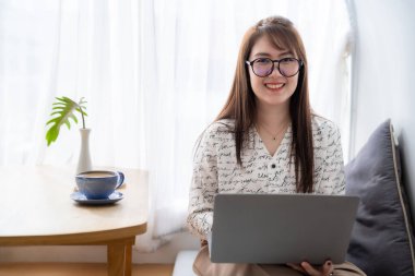 Asyalı serbest çalışanlardan memnun. İş kadını. Laptop bilgisayarı, kahve fincanı ve akıllı telefonla çalışıyor.