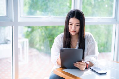 Asyalı serbest çalışan, iş kadını, akıllı şeyler giyen, günlük işleri yapan, internete girmek için tabletle çalışan, sohbet eden, blog yazan, akıllı telefon kullanan, kafede not defteri olan..