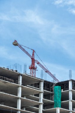 İşçiler büyük inşaat sahalarında çalışıyor ve pek çok vinç mavi gökyüzü arka planına sahip bir bina inşa ediyor..
