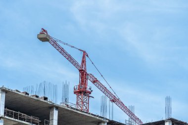 İşçiler büyük inşaat sahalarında çalışıyor ve pek çok vinç mavi gökyüzü arka planına sahip bir bina inşa ediyor..