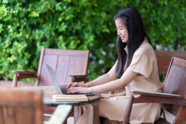 Genç Asyalı genç kız öğrencinin kafede bilgisayarla bilgisayar yazması hoşuna gidiyor. Çevrimiçi eğitim, el kazanma konsepti, serbest çalışan iş kadınları.