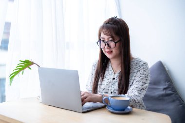 Asyalı serbest çalışan, iş kadını, akıllı şeyler giyen, sohbet eden, akıllı telefon kullanan, kahve dükkanında not defteri olan bilgisayarla günlük işler yapan..