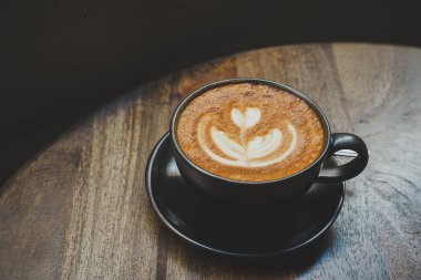 Sütlü sütlü sütlü sütlü sıcak kahve fincanı ahşap masanın üstünde. Kafedeki bir kafede kahvaltı olarak, iş konsepti sırasında, klasik tarzda.