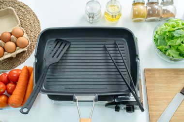 Üst taraf boş demir tava, dilimlenmiş ekmek yumurtaları, şeker, baharatlar, sebze, domates ve beyaz masanın üzerindeki mutfakta çırpılmış çırpı. Düz yatıyordu. Yemek hazırlama kavramı, arka planda mutfak..