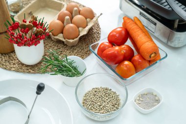 Cam bardakta biber, sebze, domates, yumurta ve beyaz masadaki mutfakta çırpı. Düz yatıyordu. Yemek hazırlama kavramı, arka planda mutfak..