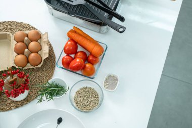 Cam bardakta biber, sebze, domates, yumurta ve beyaz masadaki mutfakta çırpı. Düz yatıyordu. Yemek hazırlama kavramı, arka planda mutfak..