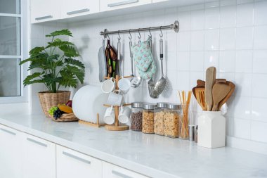 Tahıl, tahıl gevreği, cam kavanozlarda makarna ve beyaz masadaki mutfakta beyaz cam içme ekipmanları. Düzlük, yemek hazırlama kavramı, arka planda mutfak..