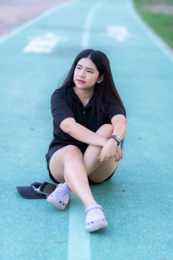 Siyah tişörtlü Asyalı bir turist portresi yolda yürüyor, bisiklet sürüyor ve parktaki köprü bahçesinde egzersiz yapıyor.