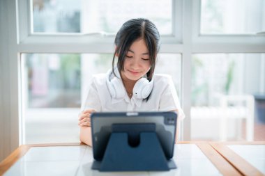 Şirin gülüşler Asyalı, kulaklık takan, müzik dinleyen, kulaklık takan, kafede çalışan bilgisayarlı çekici bir kız. Çevrimiçi eğitim, gelişim konsepti..