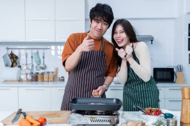 Genç Asyalıyı sevmenin mutlu portresi neşe dolu bir yemek hazırlarken yemek pişirmenin, sebze, et, ekmek pişirmenin ve bir evde ya da mutfakta hayat boyu kalmanın keyfini çıkarmanın.