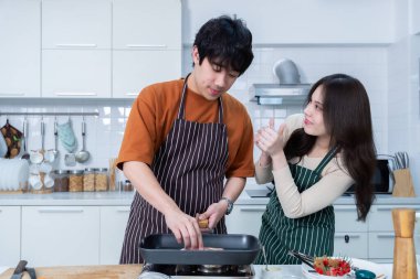 Genç Asyalıyı sevmenin mutlu portresi neşe dolu bir yemek hazırlarken yemek pişirmenin, sebze, et, ekmek pişirmenin ve bir evde ya da mutfakta hayat boyu kalmanın keyfini çıkarmanın.