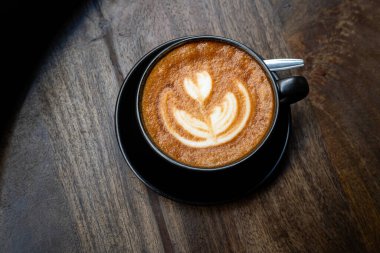 Sütlü sütlü sütlü sütlü sıcak kahve fincanı ahşap masanın üstünde. Kafedeki bir kafede kahvaltı olarak, iş konsepti sırasında, klasik tarzda.