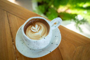 Sütlü sütlü sütlü sütlü sıcak kahve fincanı ahşap masanın üstünde. Kafedeki bir kafede kahvaltı olarak, iş konsepti sırasında, klasik tarzda.