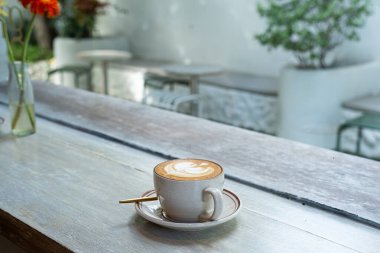 Sütlü sütlü sütlü sütlü sıcak kahve fincanı ahşap masanın üstünde. Kafedeki bir kafede kahvaltı olarak, iş konsepti sırasında, klasik tarzda.