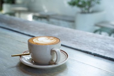 Sütlü sütlü sütlü sütlü sıcak kahve fincanı ahşap masanın üstünde. Kafedeki bir kafede kahvaltı olarak, iş konsepti sırasında, klasik tarzda.