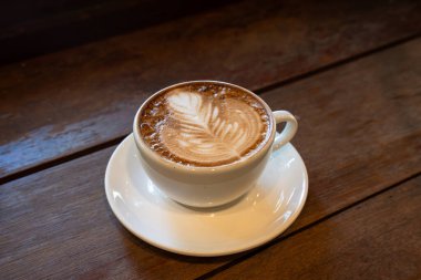 Sütlü sütlü sütlü sütlü sıcak kahve fincanı ahşap masanın üstünde. Kafedeki bir kafede kahvaltı olarak, iş konsepti sırasında, klasik tarzda.