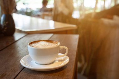 Sütlü sütlü sütlü sütlü sıcak kahve fincanı ahşap masanın üstünde. Kafedeki bir kafede kahvaltı olarak, iş konsepti sırasında, klasik tarzda.